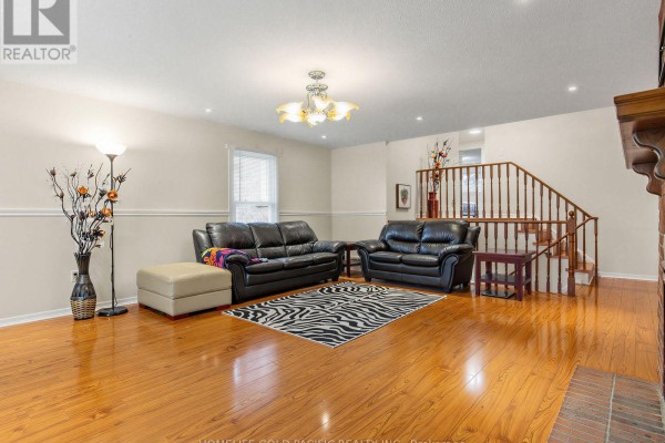Living room with black leather sofas, zebra rug, and wooden stairs - 156 Ravenscroft Road Ajax
