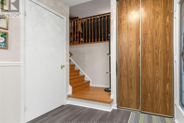 Entryway with wood-paneled sliding closet doors, stairs, and a coat rack. - 156 Ravenscroft Road, Ajax