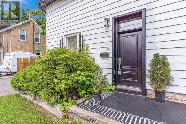 Close-up of the front door of unit 156, featuring a black door, white siding, and landscaping. - 156 St. Andrews Street, Cambridge