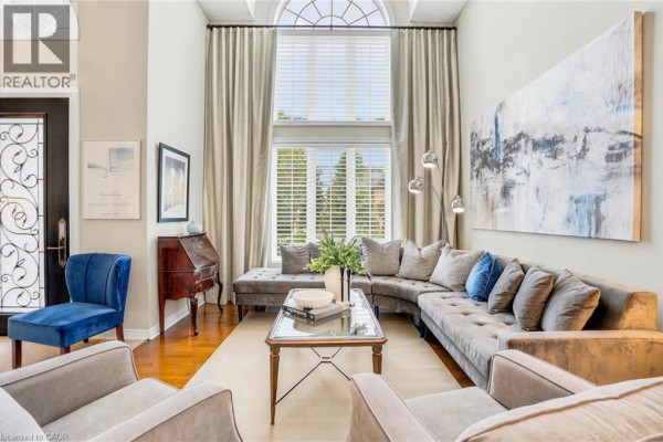 Living room with a large sectional sofa, floor-to-ceiling windows, and artwork. - 156 Valmont Street, Ancaster