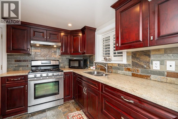 Compact kitchen with dark wood cabinets, stainless steel appliances, and stone accents - 1562 W 62nd Avenue, Vancouver