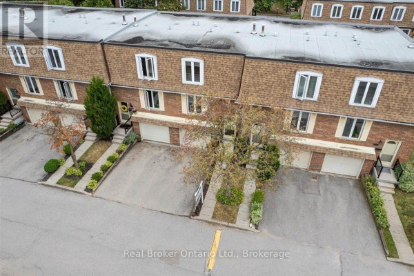 Aerial view of townhouse complex showing multiple units with garages and brown shingled roofs. - 1569 Westminster Place, Burlington