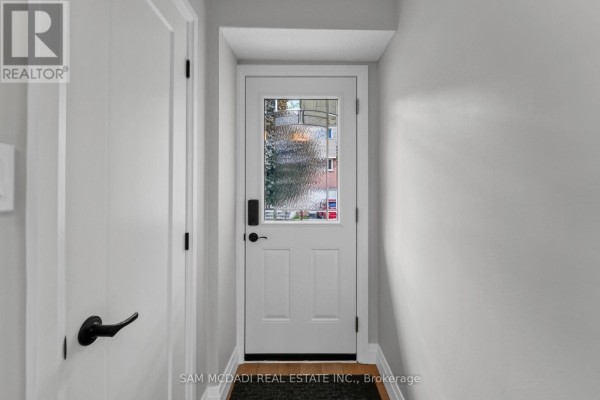 Interior view of a white front door with a glass pane, set in a hallway with light grey walls. - 157 - 400 Mississauga Valley Boulevard, Mississauga