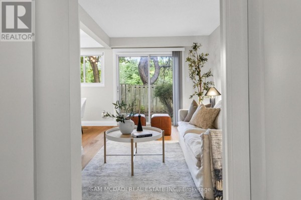 Living room with a white sofa, coffee table, and a sliding glass door leading to an outdoor patio. - 157 - 400 Mississauga Valley Boulevard, Mississauga