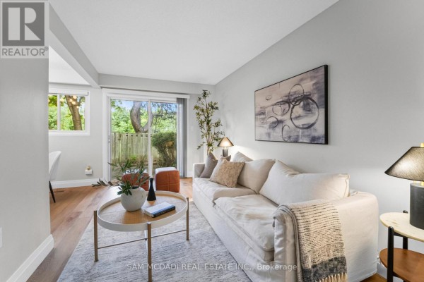 Living room featuring a light-colored sofa, a round coffee table, and artwork above the sofa on a grey wall. - 157 - 400 Mississauga Valley Boulevard, Mississauga
