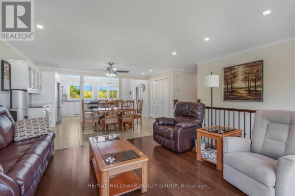 Open concept living and dining area with a kitchen, large wooden table, and sofas. - 157 Concession 1 Road, Alfred And Plantagenet