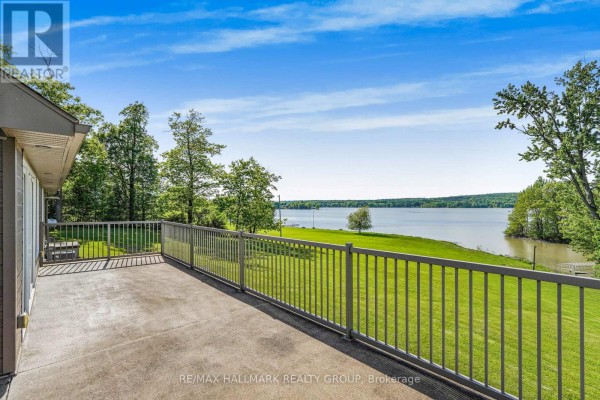 Concrete deck with metal railing offering a view of a grassy yard and a wide calm body of water. - 157 Concession 1 Road, Alfred And Plantagenet