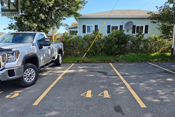 Parking spaces numbered 4 and 5 with a silver pickup truck parked in space 5. - 157 Forest Road Unit#65, St  John S