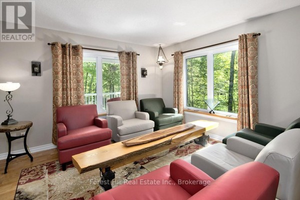 A screened-in gazebo with a stone pathway and landscaped gardens in a sunlit wooded area. - 157 Glen Fiddish Road, West Grey
