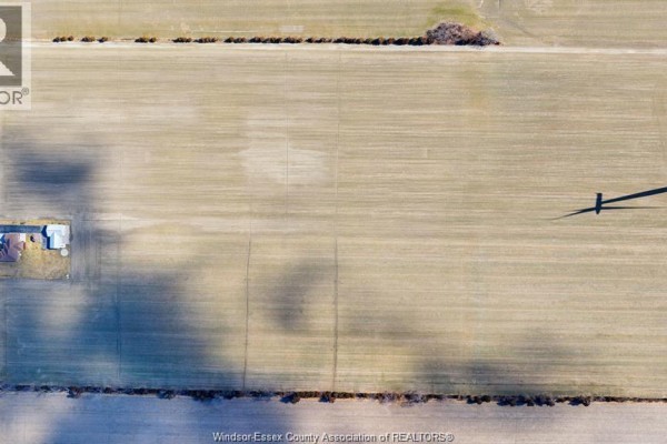 Close-up aerial view of a vast, light brown agricultural field with rows, showing shadows and a small building. - 157 Road 7, Kingsville