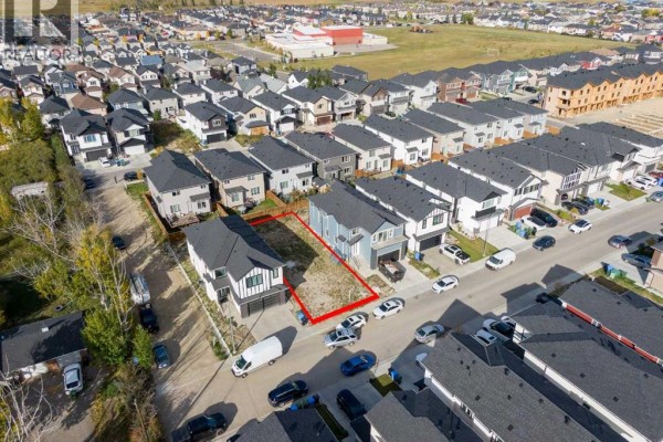Aerial view shows a residential lot, outlined in red, nestled between completed homes on Saddlecrest Circle. - 157 Saddlecrest Circle Ne, Calgary
