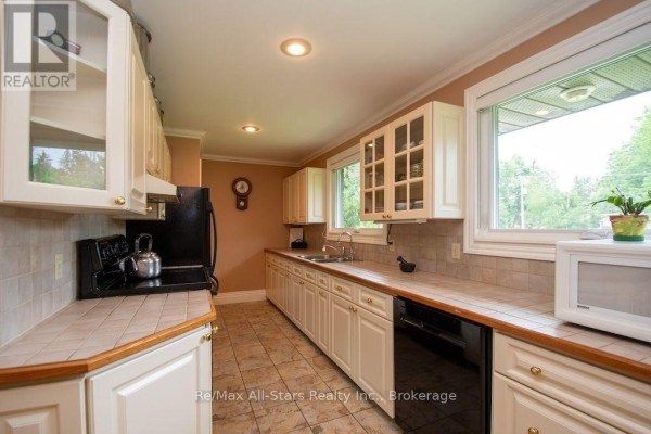 Kitchen with white cabinets, tile countertops, and a large window - 1571 Elm Tree Road Kawartha Lakes