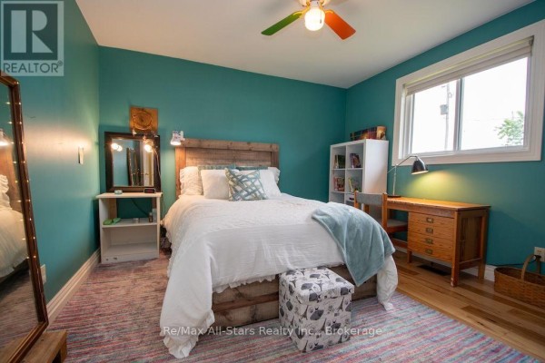 Bedroom with teal walls, king bed, rustic headboard, ottoman, desk, bookshelf, and mirror - 1571 Elm Tree Road Kawartha Lakes