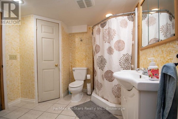 Bathroom with pedestal sink, toilet, and patterned shower curtain - 1571 Elm Tree Road Kawartha Lakes