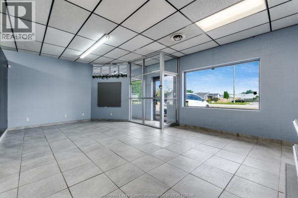 Interior of empty commercial space with large window facing a street view. - 1571 Seacliff Drive Unit# 3, Kingsville