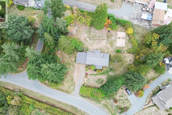 Aerial view of a single-family home on a wooded lot with surrounding roads and other houses. - 1571 Tatlo Rd W, Crofton