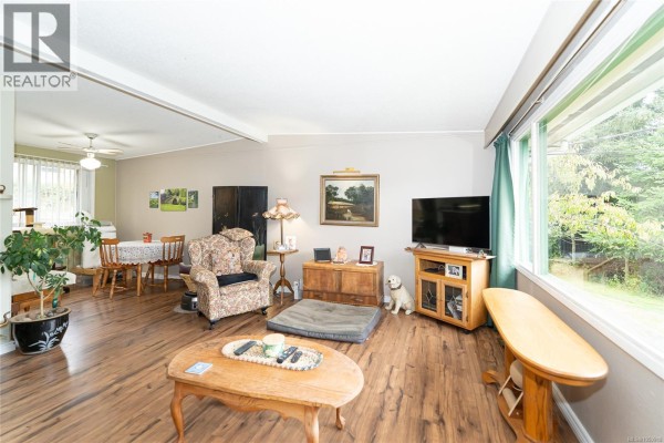 Living room with wood-look flooring, a sofa, armchair, coffee table, and large window. - 1571 Tatlo Rd W, Crofton
