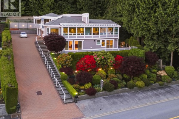 Exterior of a modern house with grey siding, large windows, and lush landscaping. - 1574 Chartwell Drive, West Vancouver
