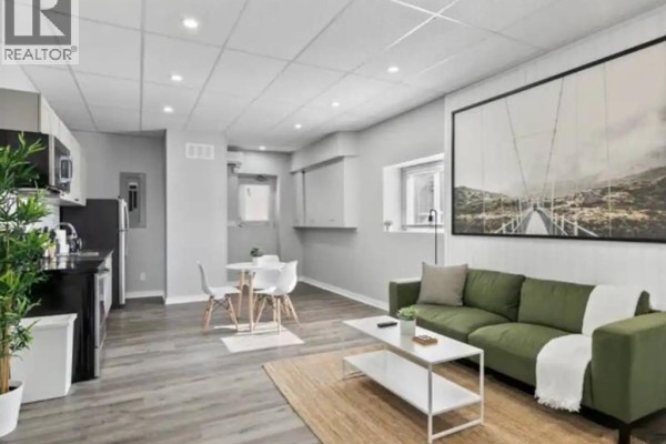 Open concept studio with kitchen, dining area, and living space with large artwork. - 1574 Howard Avenue, Windsor