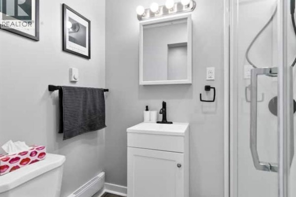 Small bathroom vanity with white sink, black faucet, and towel bar on light gray wall. - 1574 Howard Avenue, Windsor