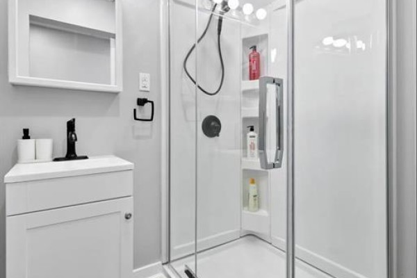 Corner shower stall with glass doors, white shelves, and black faucet fixture. - 1574 Howard Avenue, Windsor