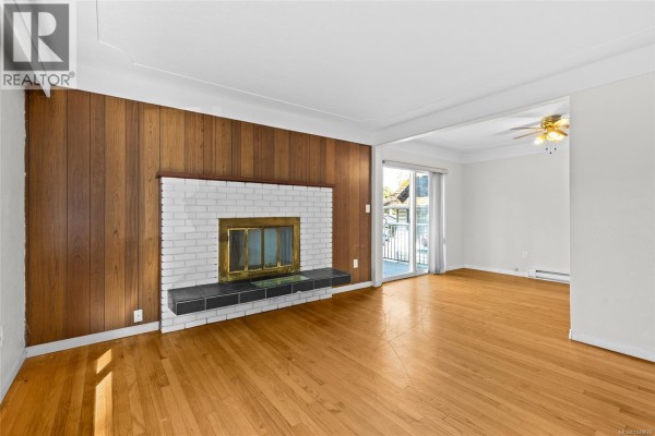 Open concept living area with hardwood floors, leading to a kitchen with oak cabinets and tiled backsplash. - 1575 Burton Ave, Victoria