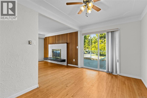 Bedroom with light grey walls, a window overlooking trees, and hardwood floors with sunlight streaming in. - 1575 Burton Ave, Victoria