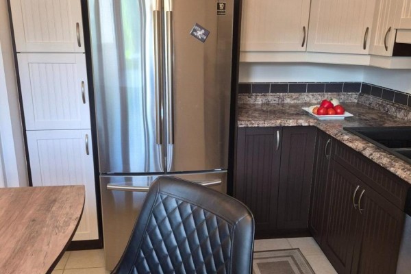 Stainless steel refrigerator next to white pantry cabinets in a corner kitchen. - 1576 Lassiter Terrace, Ottawa
