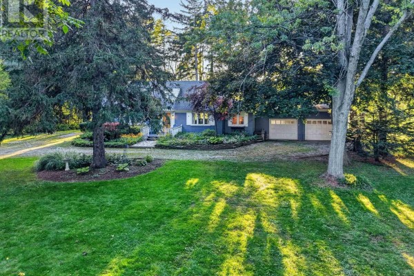 Front view of a blue ranch-style house with a white-trimmed roof and two attached garage doors. - 1577 Gregory Road, St  Catharines