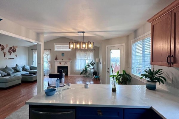 Open-concept living and dining area with a fireplace, sectional sofa, and kitchen island. - 1577 Purser Street, London East