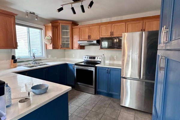 U-shaped kitchen with oak cabinets, blue lower cabinets, stainless steel appliances, and a double sink. - 1577 Purser Street, London East