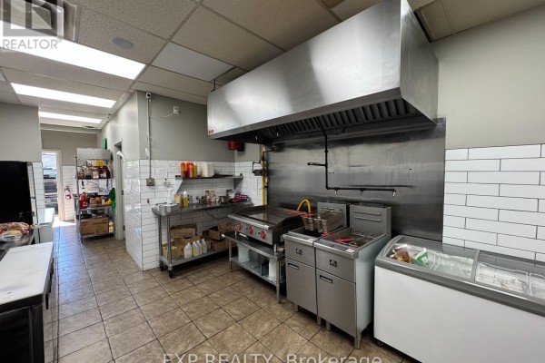 Commercial kitchen with stainless steel surfaces, fryers, stove, and refrigeration units. - 1579 Oxford Street E, London East