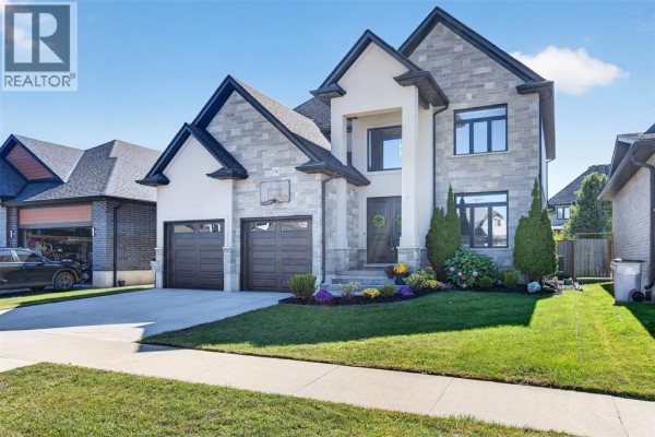 Front exterior view of a modern two-story house with a stone and stucco facade and a three-car garage. - 158 Acton Street, Strathroy