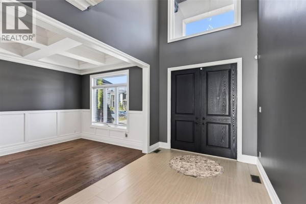 Interior view of a grand foyer with double black doors, a coffered ceiling dining room, and hardwood floors. - 158 Acton Street, Strathroy