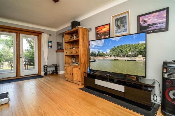 Living room with hardwood floors, a white sofa, black recliners, and a desk with a treadmill. - 158 Glenwood Crescent, Winnipeg