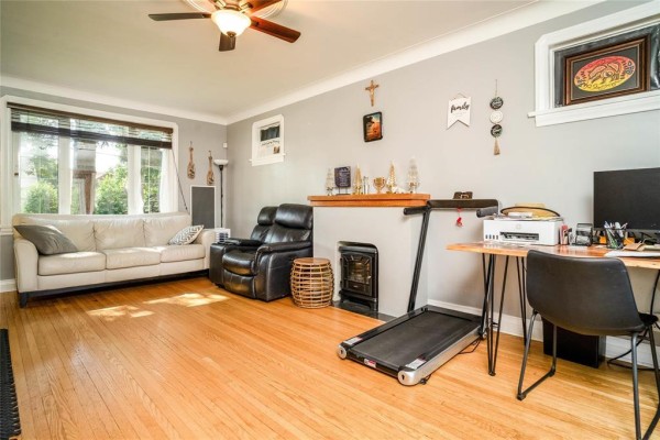 Living room featuring a fireplace, a large television, a sofa, and hardwood floors. - 158 Glenwood Crescent, Winnipeg