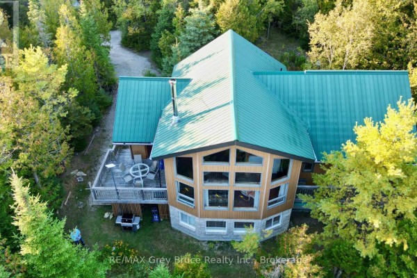 Aerial view of a house with a large multi-pane window wall and a wooden deck. - 158 Hobson's Harbour Drive, Northern Bruce Peninsula