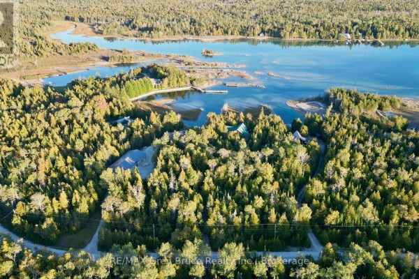 Aerial view of the house nestled amongst trees with a body of water in the distance. - 158 Hobson's Harbour Drive, Northern Bruce Peninsula