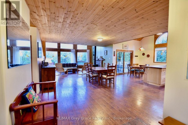Open concept living area with wood floors, wood ceiling, fireplace, and large windows. - 158 Hobson's Harbour Drive, Northern Bruce Peninsula