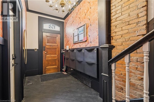 Entranceway with a wooden door, black mailbox bank, and exposed brick wall. - 158 Hunter Street E, Hamilton