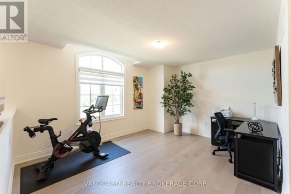 Home gym area with a Peloton bike, yoga mat, desk, and chair. - 158 Scarlet Way, Bradford West Gwillimbury