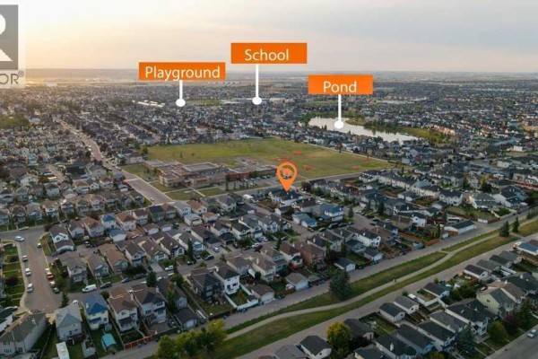 Aerial view of a suburban neighborhood showing houses, a school, playground, and a pond. - 158 Taralea Circle Ne, Calgary