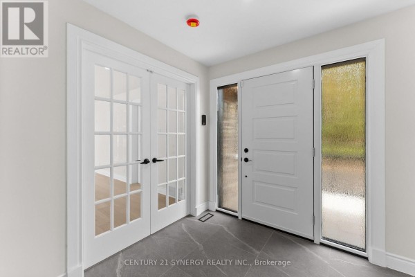 Interior front entrance with white double doors with glass panes, white front door, and large frosted glass window. - 1580 Groves Road, Russell