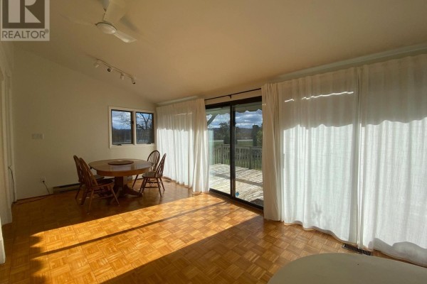 Sunlit dining area with wood table, parquet flooring, and patio doors. - 1581 Line 6 Road, Niagara On The Lake
