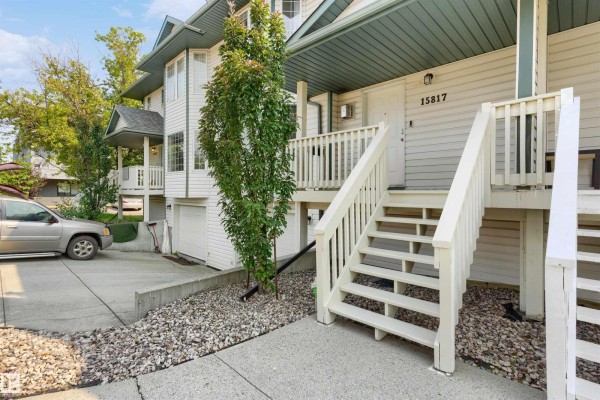Close-up of townhouse entrance with white stairs, railings, and siding numbered 15817. - 15817 102 Av Nw, Edmonton