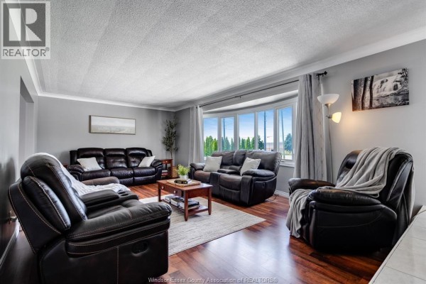 Living room with dark leather sofas and chairs, a bay window, and hardwood floors. - 1582 County Rd 34, Ruthven