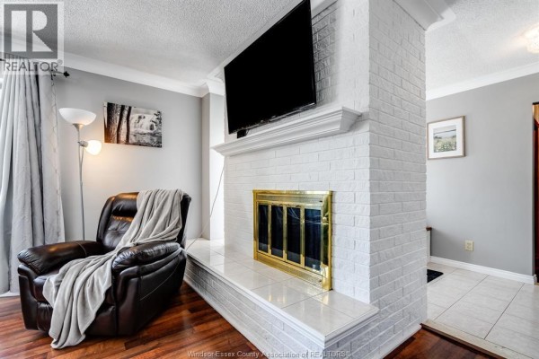 Living room with a white brick fireplace, television mounted above, and a brown leather recliner. - 1582 County Rd 34, Ruthven