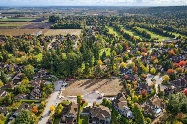 Aerial view of a cleared lot surrounded by homes, a golf course, and distant farmland. - 15826 36 Avenue, Surrey