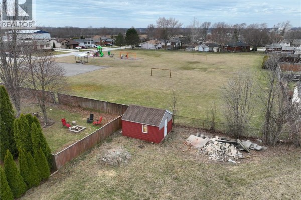 Aerial view showing a red shed on a grassy lot, with a playground and sports fields in the background. - 1583 Councillors Street, Moore Township