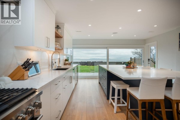 Long kitchen island with white countertops and seating, overlooking the ocean. - 1584 Beach Grove Road, Delta